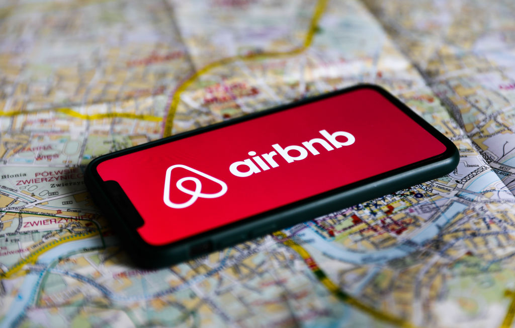 Airbnb logotipas ir mobilus telefonas su programa
